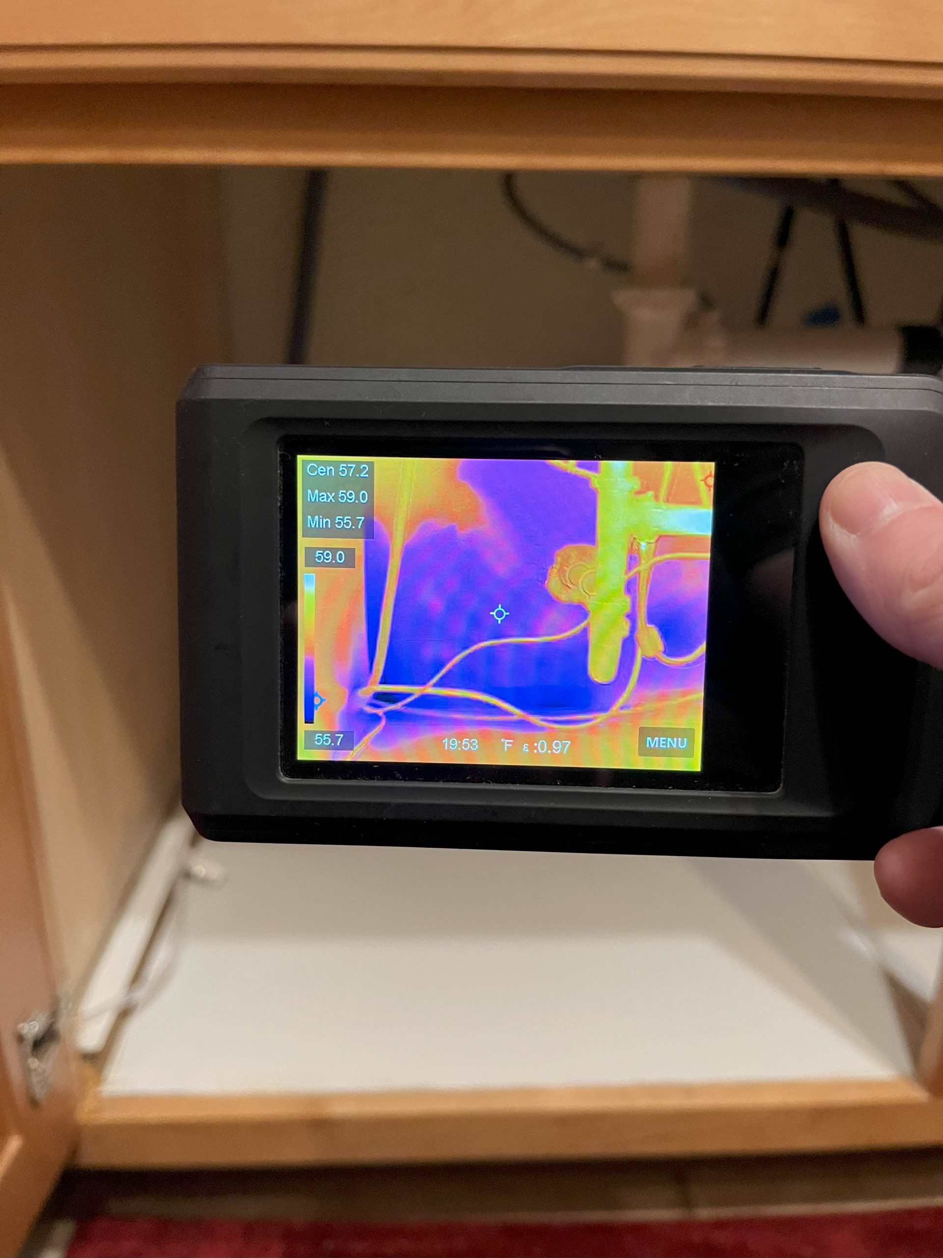 Water Damage Technician inspects a possible water leak under a kitchen sink using a thermal camera in Mesa AZ